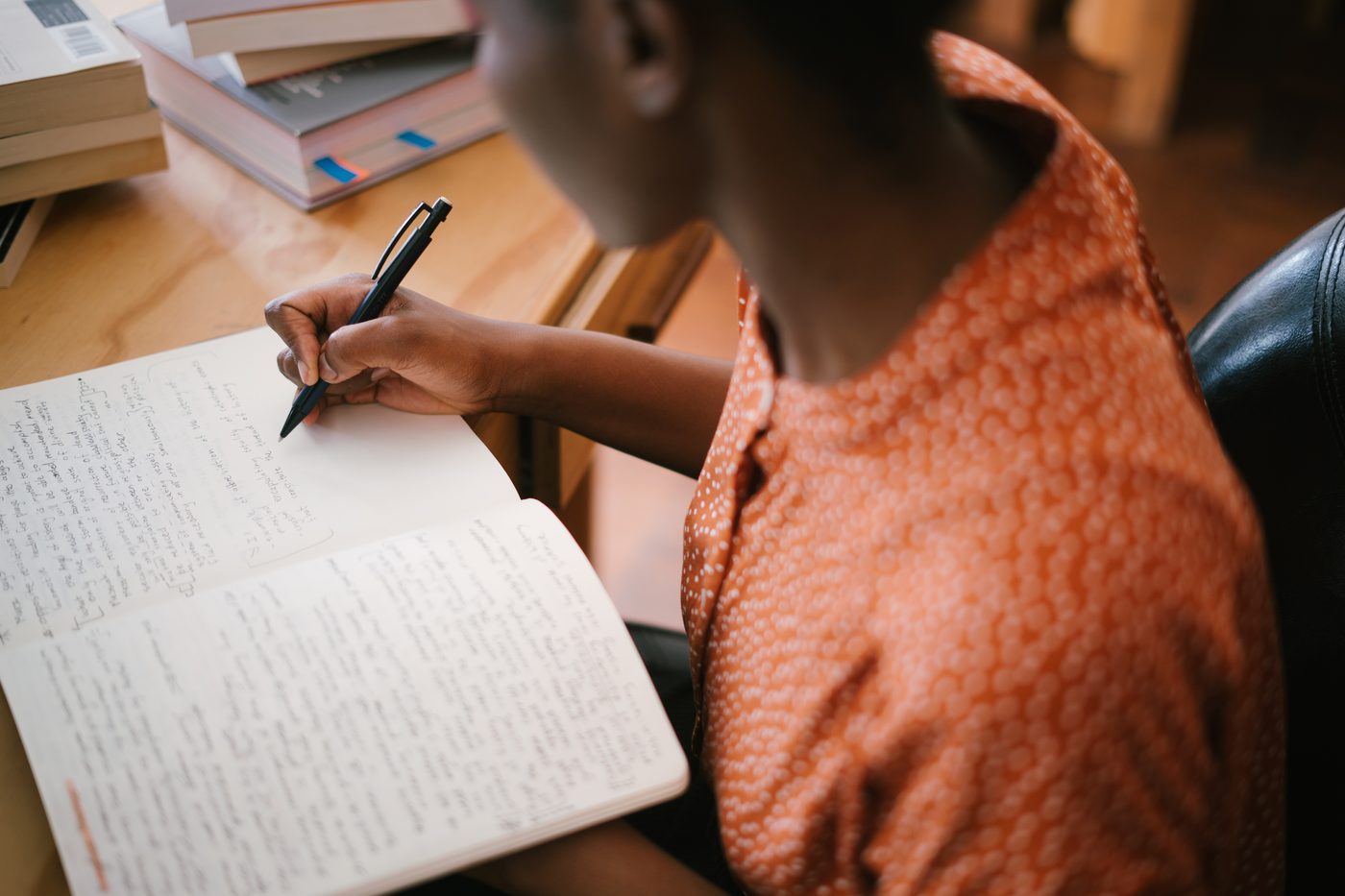A person writing in a notebook at a desk