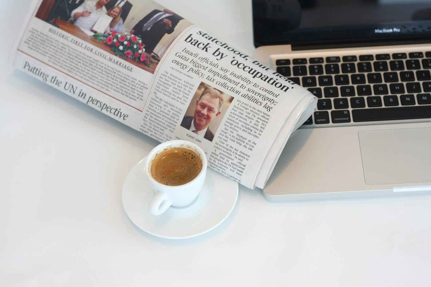Newspaper and a cup of coffee beside a laptop